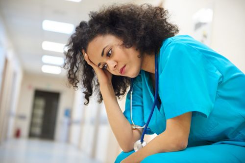 Overworked Nurse Sitting in Hospital Hall