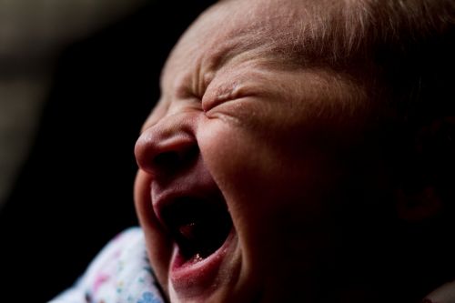 Close-up portrait shot of a newborn baby while crying.