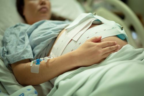 A pregnant woman being induced in the hospital, with iv and contractions monitor.