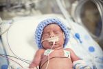 Premature newborn baby being treated in intensive care as he is hooked up to an IV and health monitors